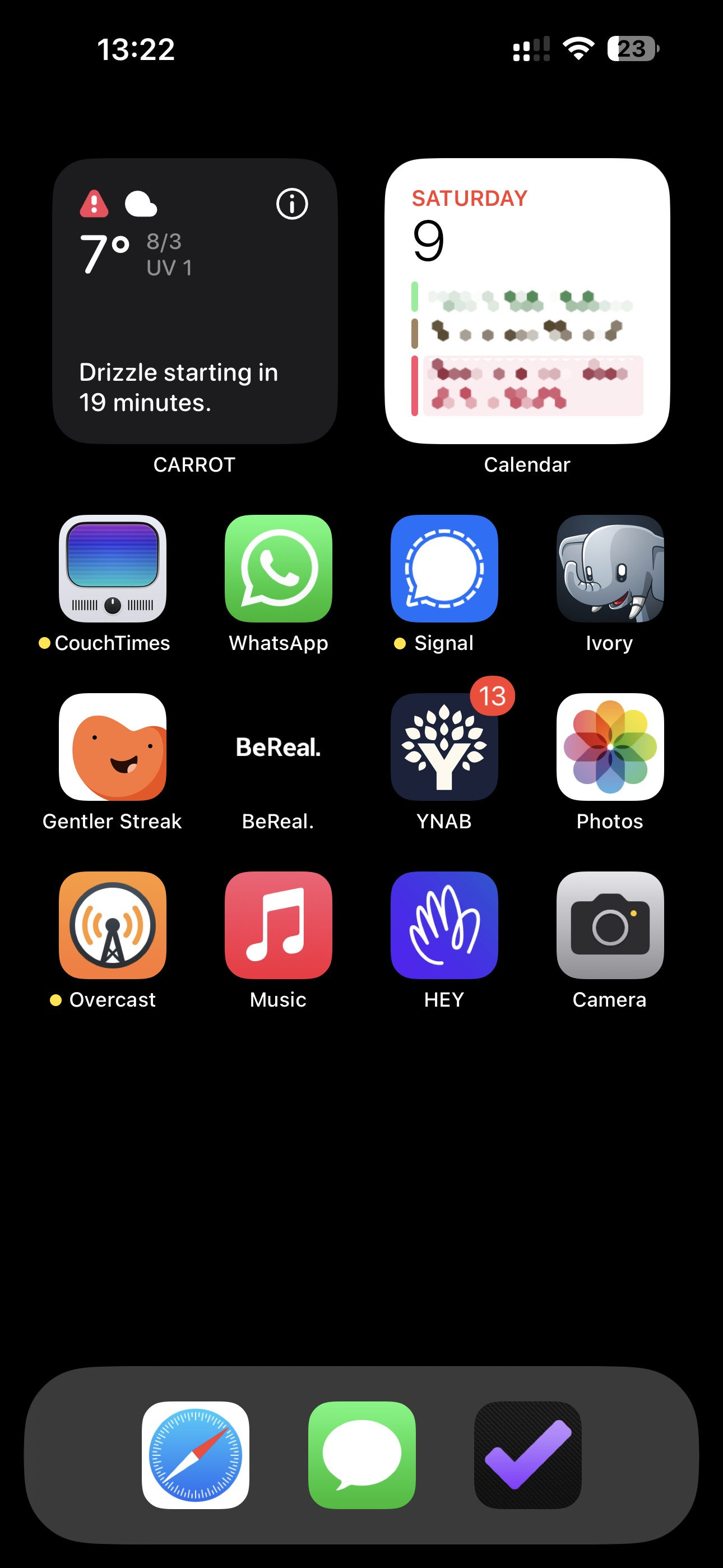 An iPhone Home Screen with a black background. At the top are two small widgets: CARROT weather and Calendar. Below that are three rows of apps: CouchTimes, WhatsApp, Signal, Ivory, Gentler Streak, BeReal, YNAB, Photos, Overcast, Music, HEY and Camera. The dock has three apps: Safari, Messages & OmniFocus 4